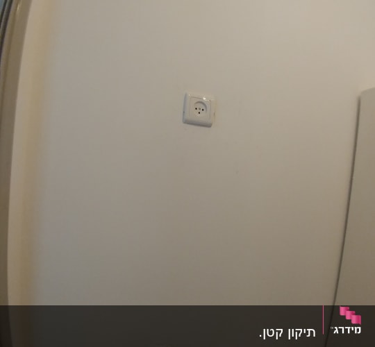 שקע חשמל על קיר לבן עם צינורות מתכת